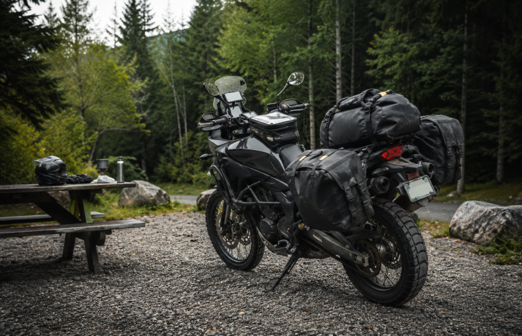 Moto adventure con borse morbide e borsa da sella in un'area di sosta nel bosco