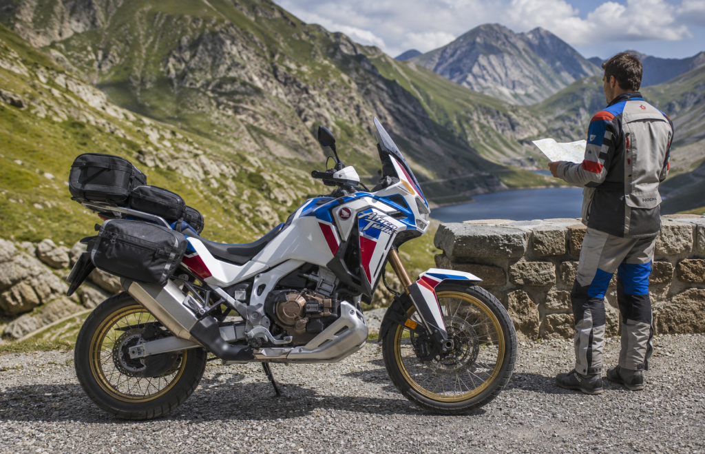 Motociclista in sosta accanto a una Honda Africa Twin con mappa in mano