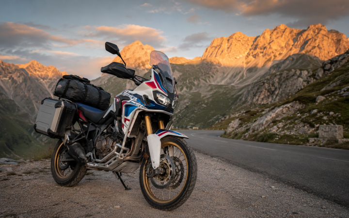 Honda Africa Twin con bagagli su un passo alpino al tramonto